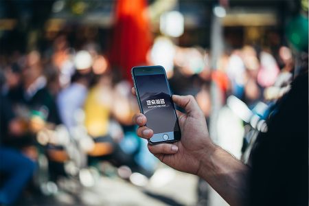 模糊人群背景男士手拿黑色iPhone6高清场景样机素材