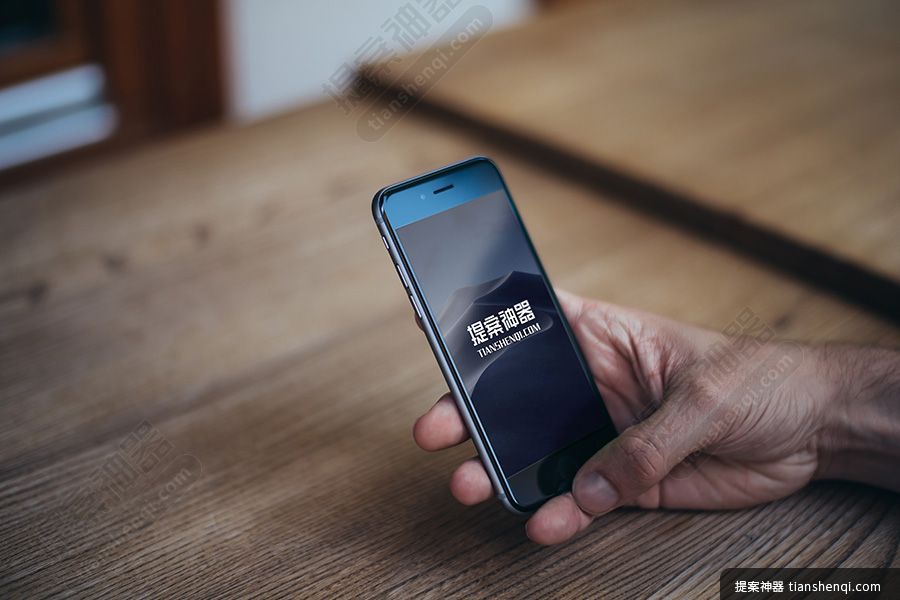高清木质桌上单手拿iPhone6样机素材